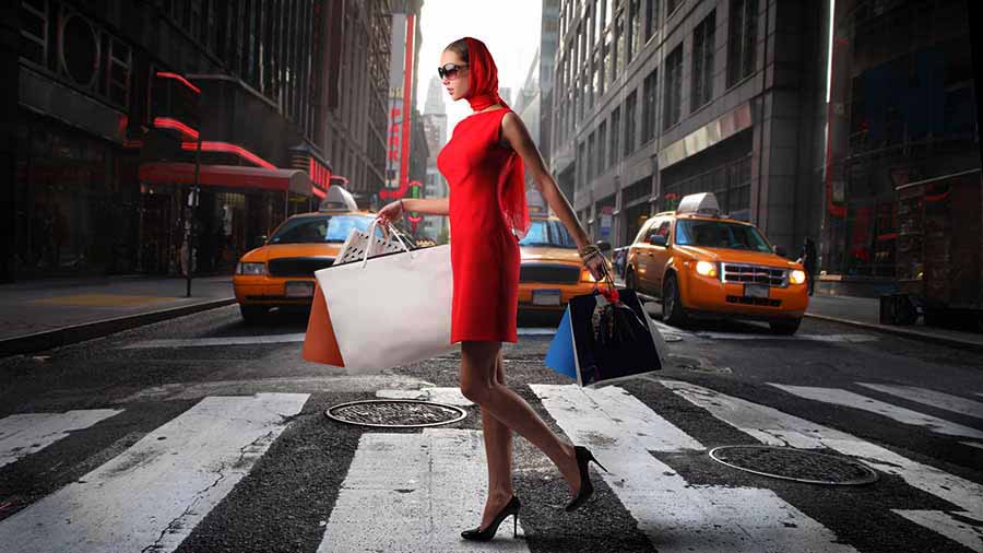 mujer de rojo con tacones de aguja y bolsas de compra cruza la calle