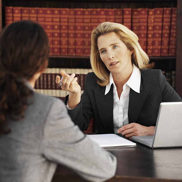 abogada sentada en su despacho habla con una clienta