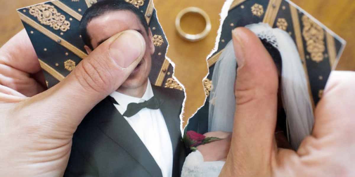 manos rompiendo foto de boda y anillo encima de la mesa